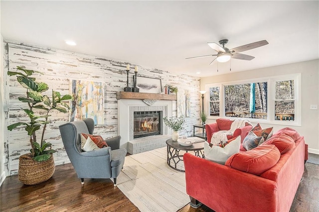 living room with a fireplace, ceiling fan, and wood finished floors