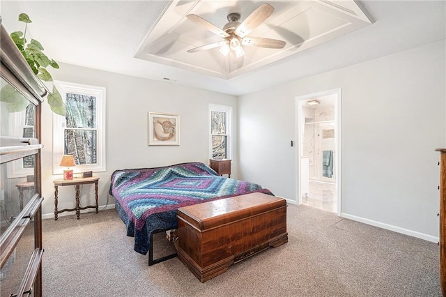 carpeted bedroom with visible vents, baseboards, ceiling fan, ensuite bathroom, and a raised ceiling