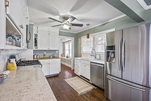 kitchen featuring white cabinets, decorative light fixtures, stainless steel appliances, crown molding, and a sink