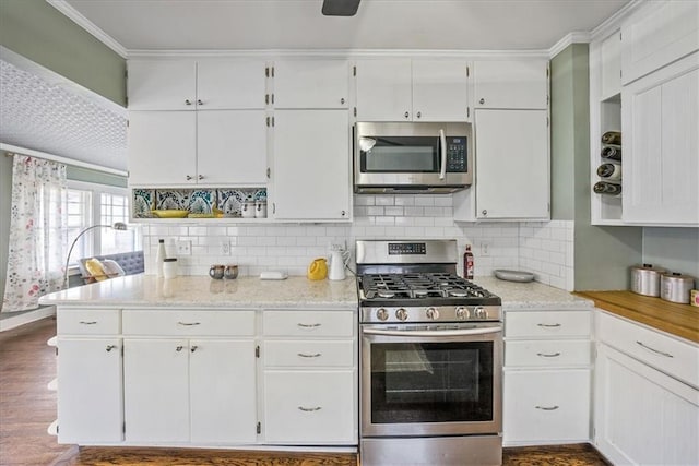 kitchen featuring tasteful backsplash, dark wood-style floors, appliances with stainless steel finishes, crown molding, and white cabinetry