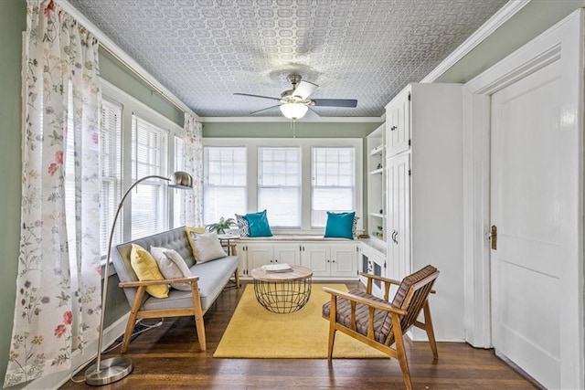 sitting room featuring dark wood-style floors, an ornate ceiling, ornamental molding, and ceiling fan