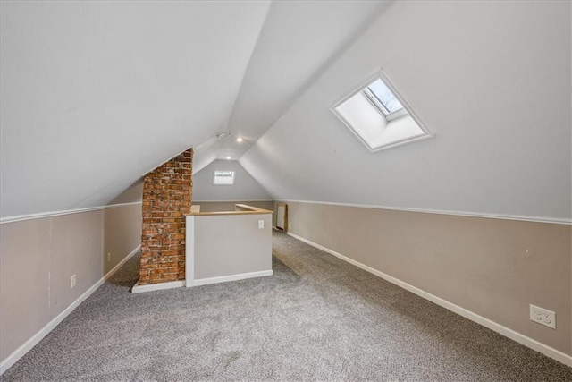 additional living space featuring vaulted ceiling with skylight, carpet, and baseboards