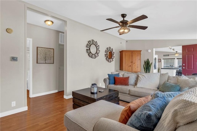 living room featuring baseboards, a ceiling fan, and wood finished floors