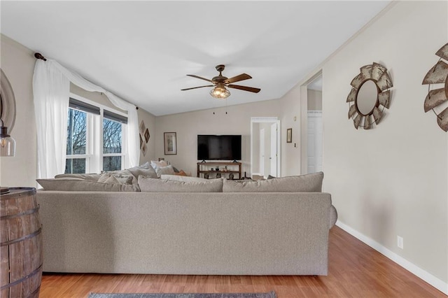 living room featuring a ceiling fan, light wood-type flooring, vaulted ceiling, and baseboards