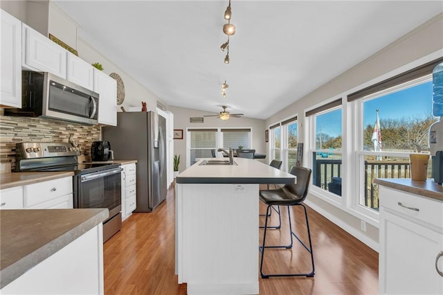 kitchen featuring light wood-style flooring, a sink, white cabinets, appliances with stainless steel finishes, and decorative backsplash