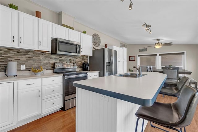 kitchen featuring decorative backsplash, a kitchen breakfast bar, vaulted ceiling, stainless steel appliances, and a sink