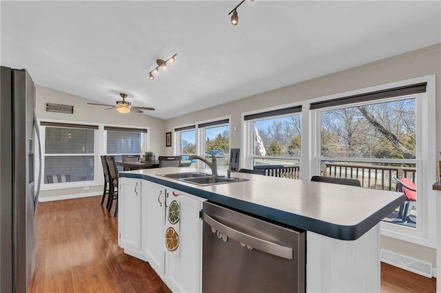 kitchen featuring visible vents, lofted ceiling, wood finished floors, stainless steel appliances, and a sink