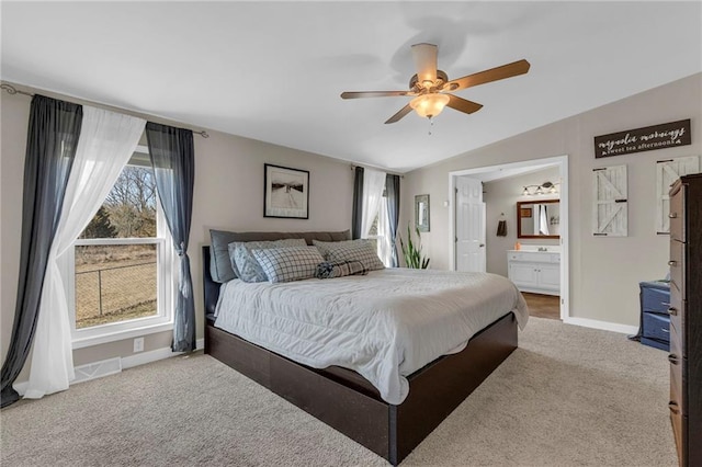 carpeted bedroom featuring visible vents, baseboards, lofted ceiling, ensuite bath, and ceiling fan