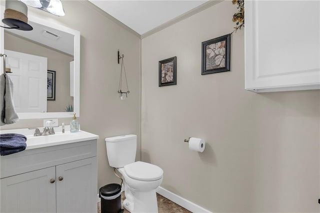 half bath with toilet, visible vents, baseboards, vanity, and crown molding