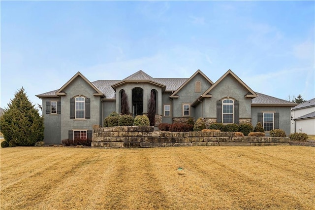 french country home featuring a front lawn and stucco siding