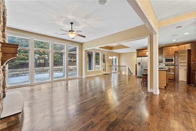 unfurnished living room featuring dark wood-style floors, a ceiling fan, and baseboards