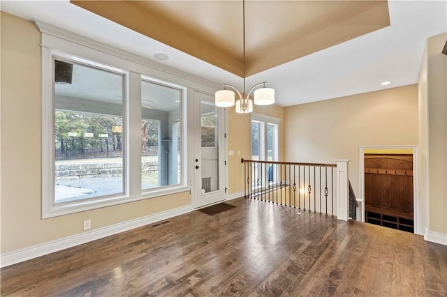 unfurnished room featuring a raised ceiling, visible vents, baseboards, and wood finished floors