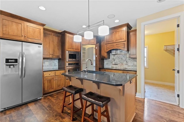 kitchen featuring appliances with stainless steel finishes, brown cabinets, a sink, and a kitchen bar