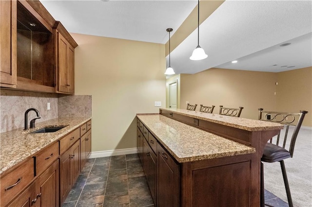 kitchen featuring a peninsula, a sink, baseboards, a kitchen breakfast bar, and decorative backsplash