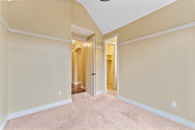 unfurnished bedroom with arched walkways, lofted ceiling, visible vents, carpet flooring, and baseboards