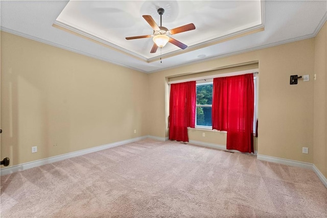 carpeted empty room featuring ornamental molding, a raised ceiling, a ceiling fan, and baseboards