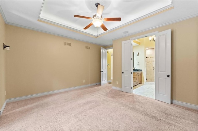 unfurnished bedroom with baseboards, a tray ceiling, ornamental molding, and light colored carpet