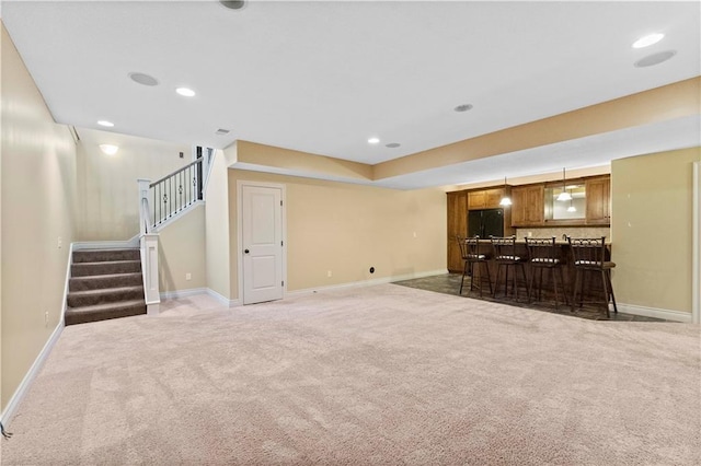 living area with recessed lighting, light colored carpet, baseboards, stairway, and a bar