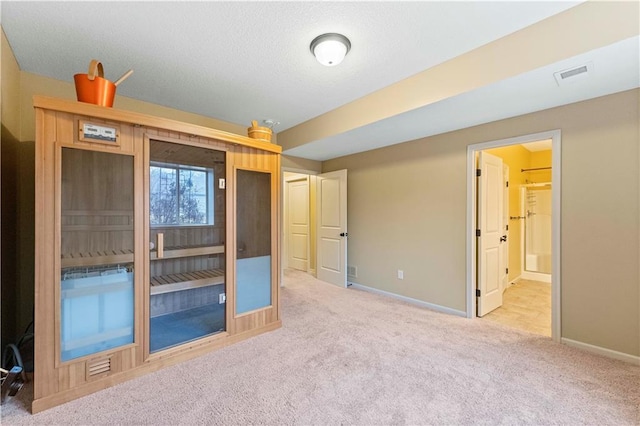 unfurnished bedroom featuring visible vents, ensuite bathroom, carpet flooring, a textured ceiling, and baseboards