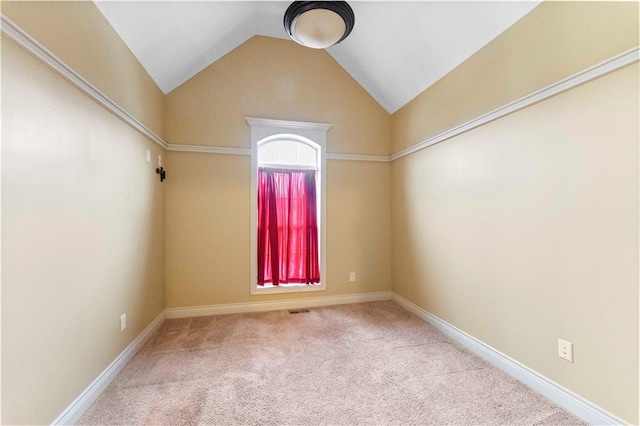 carpeted empty room with baseboards and vaulted ceiling