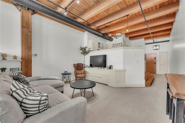 carpeted living area with wooden ceiling, a high ceiling, beam ceiling, and rail lighting