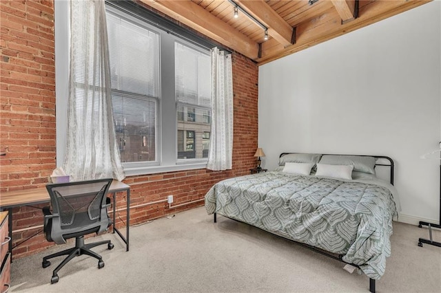 carpeted bedroom featuring wood ceiling, brick wall, track lighting, and beamed ceiling