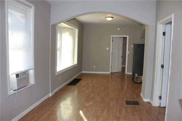 interior space with arched walkways, visible vents, baseboards, and wood finished floors