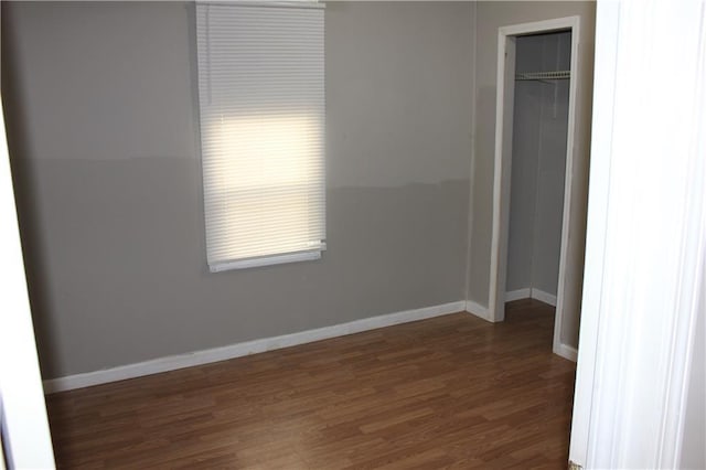 unfurnished bedroom featuring a closet, baseboards, and dark wood-style flooring