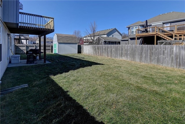 view of yard with an outbuilding, a patio, a fenced backyard, a wooden deck, and a shed