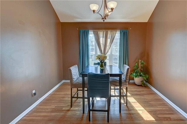 dining room featuring a chandelier, light wood-style flooring, and baseboards