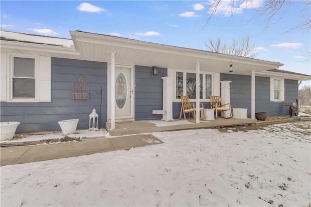 snow covered property entrance featuring a porch