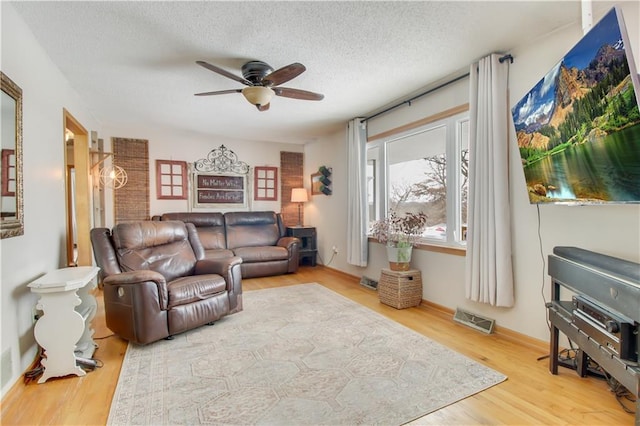 living area featuring a textured ceiling, wood finished floors, visible vents, and a ceiling fan