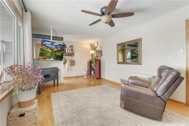 living area featuring visible vents, ceiling fan, a textured ceiling, and wood finished floors