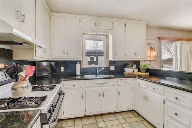 kitchen with dark countertops, white cabinetry, and a sink