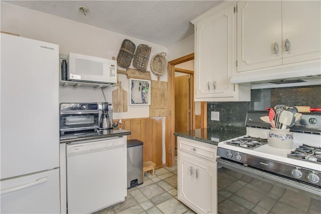 kitchen featuring white appliances, a textured ceiling, under cabinet range hood, white cabinetry, and backsplash