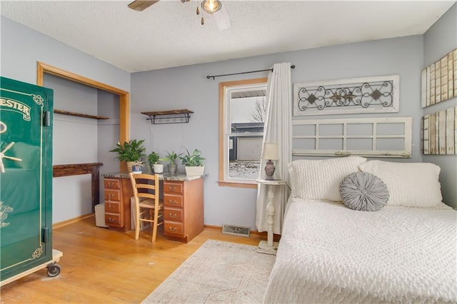 bedroom featuring baseboards, visible vents, ceiling fan, and wood finished floors