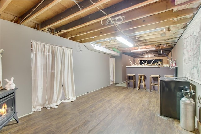 unfinished below grade area featuring wood finished floors and a wood stove