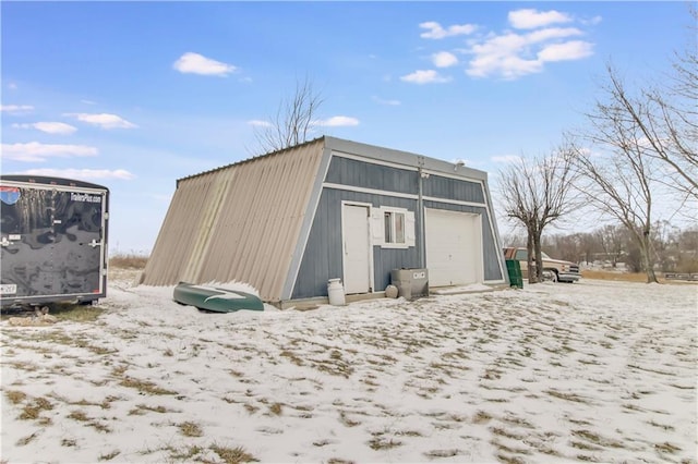 snow covered structure with an outbuilding