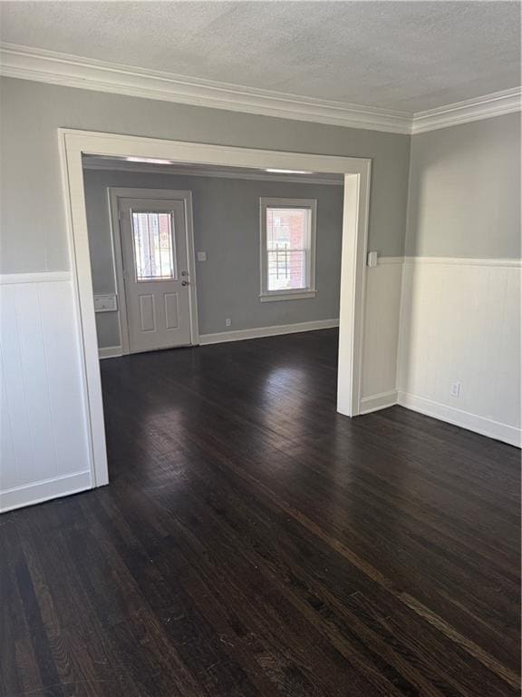 entryway featuring ornamental molding, dark wood-style flooring, wainscoting, and a textured ceiling