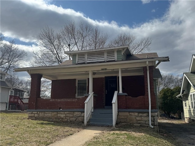 bungalow-style home featuring covered porch and brick siding