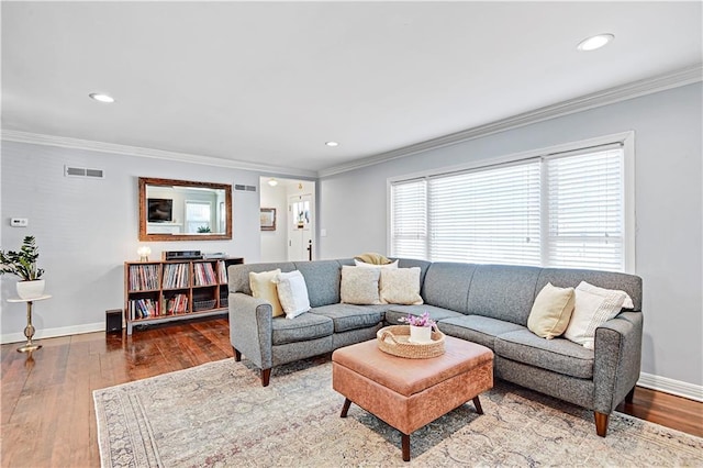 living room with baseboards, hardwood / wood-style floors, visible vents, and crown molding