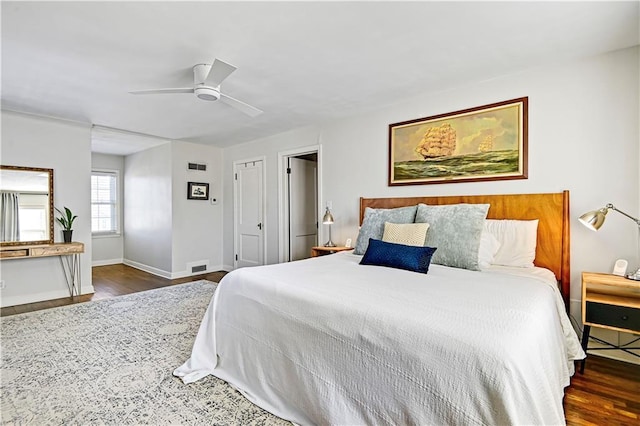 bedroom featuring a ceiling fan, dark wood-style flooring, visible vents, and baseboards