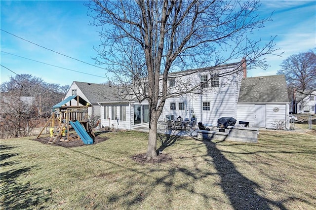 rear view of house featuring a patio area, a shingled roof, a lawn, and a playground