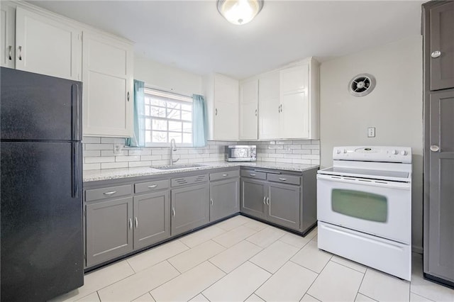 kitchen with decorative backsplash, freestanding refrigerator, white electric range, gray cabinetry, and a sink