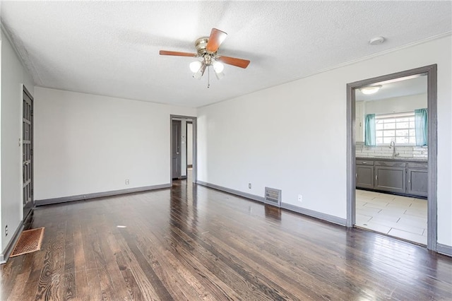 empty room with visible vents, a textured ceiling, and wood finished floors