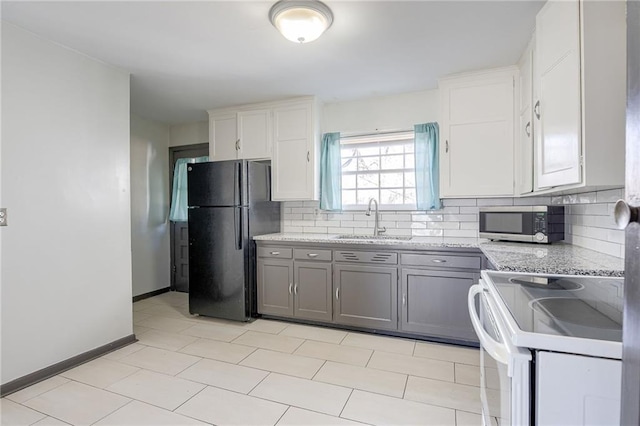 kitchen featuring gray cabinets, white electric range, stainless steel microwave, freestanding refrigerator, and a sink