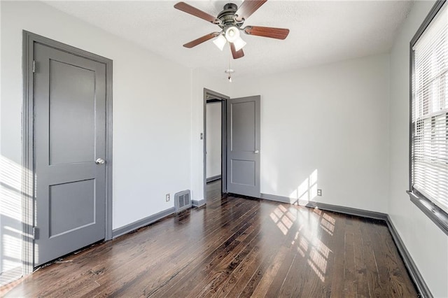 unfurnished bedroom featuring visible vents, baseboards, ceiling fan, and dark wood-style flooring