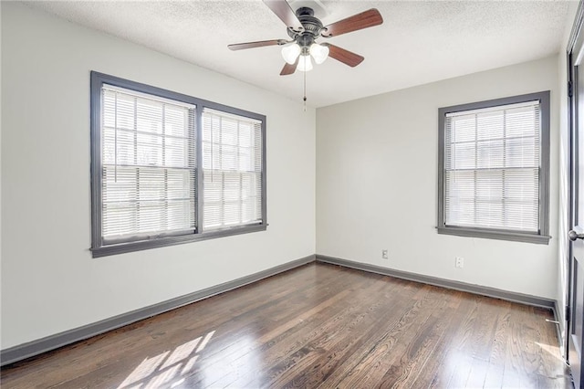 unfurnished room with a textured ceiling, wood finished floors, and baseboards