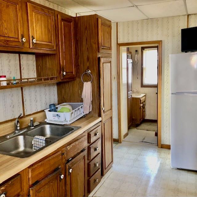 kitchen with freestanding refrigerator, light countertops, light floors, and wallpapered walls