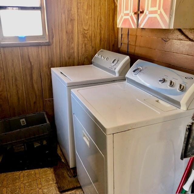 laundry area with washing machine and clothes dryer, cabinet space, and wooden walls